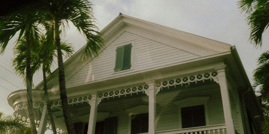 Historic white conch house with shaded veranda and palm trees