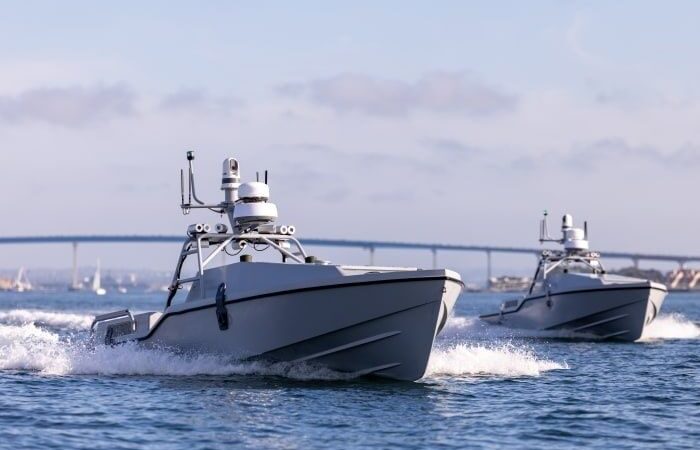 Two autonomous-looking marine vessels traveling across coastal waters